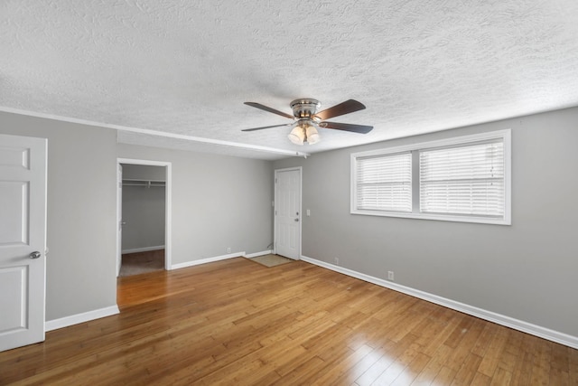 unfurnished bedroom featuring hardwood / wood-style flooring, ceiling fan, a textured ceiling, and a closet