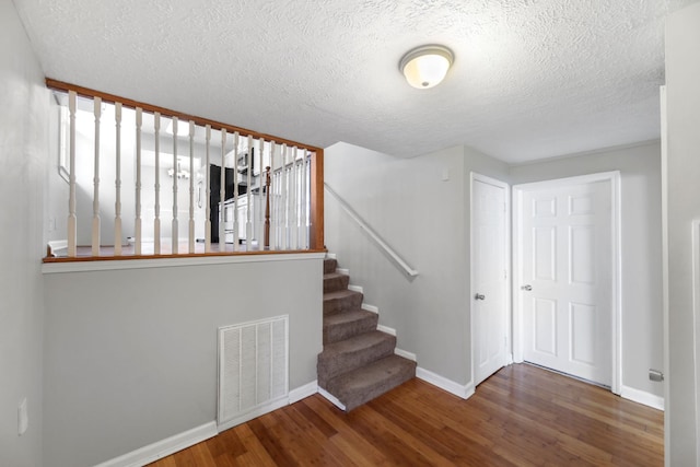 stairway featuring hardwood / wood-style floors and a textured ceiling