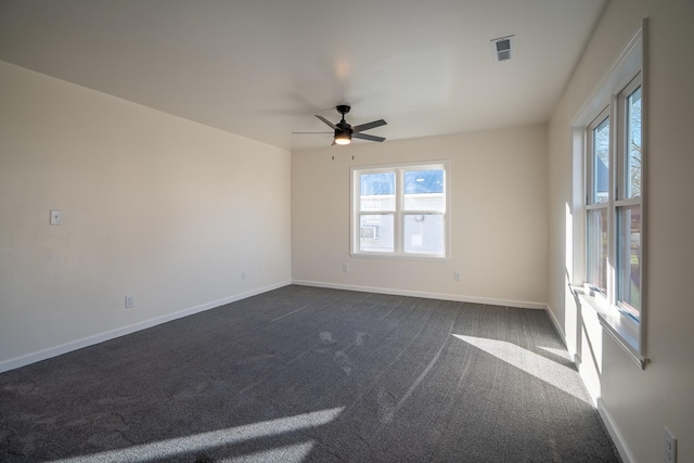 spare room featuring dark colored carpet, ceiling fan, and a healthy amount of sunlight