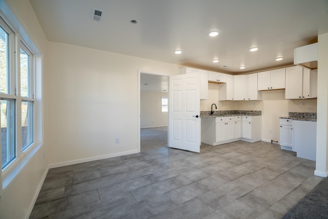 kitchen featuring dark stone countertops and white cabinetry