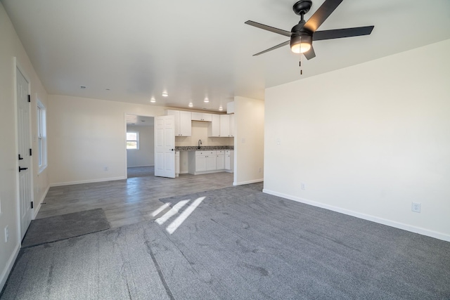 unfurnished living room with ceiling fan and sink