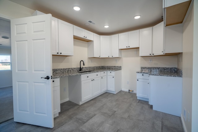 kitchen featuring white cabinetry, sink, and dark stone counters