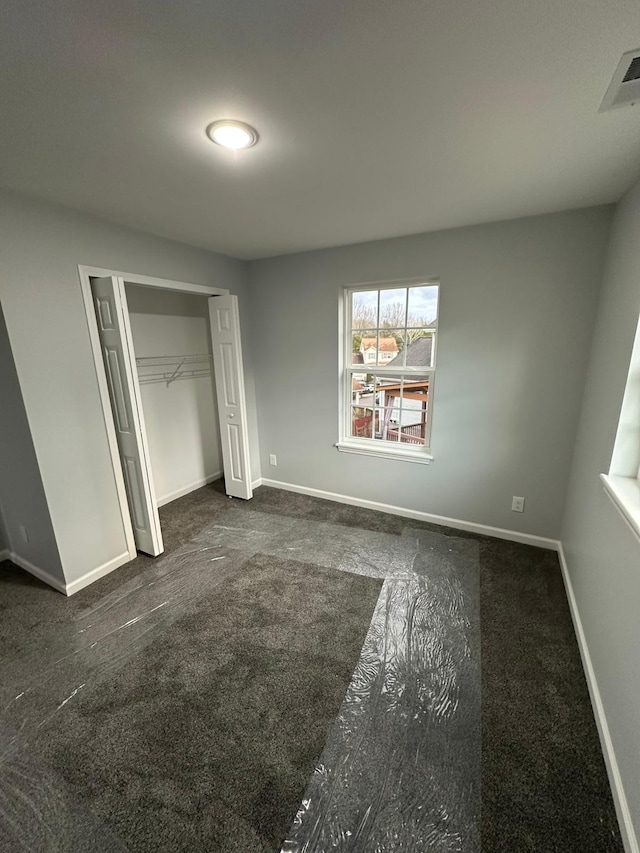 unfurnished bedroom with a closet and dark carpet