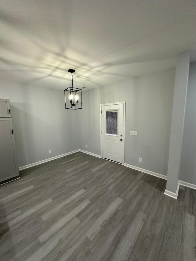 unfurnished dining area with a notable chandelier and dark hardwood / wood-style floors