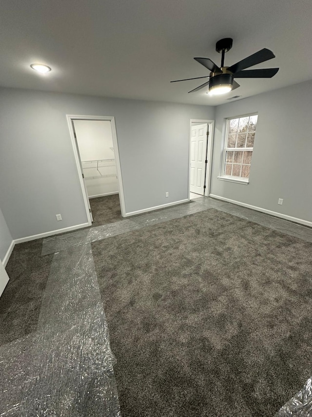 unfurnished bedroom featuring a walk in closet, a closet, and ceiling fan