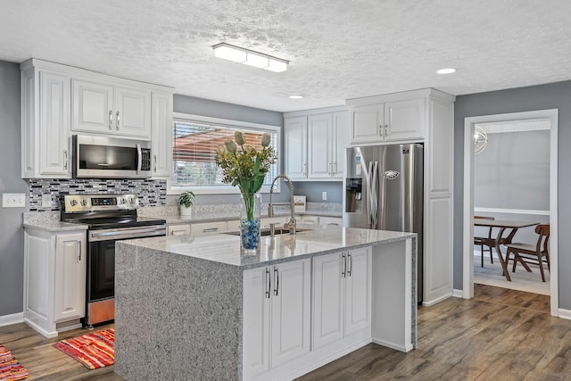 kitchen featuring sink, white cabinetry, stainless steel appliances, and an island with sink