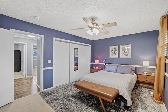 bedroom featuring carpet flooring, a textured ceiling, a closet, and ceiling fan