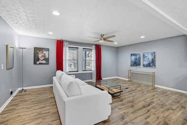 living room featuring hardwood / wood-style floors, a textured ceiling, and ceiling fan