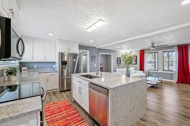 kitchen with white cabinetry, a center island with sink, sink, and appliances with stainless steel finishes