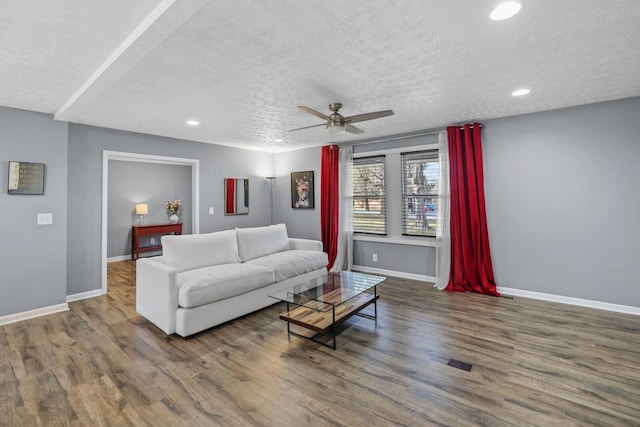 living room featuring ceiling fan, dark hardwood / wood-style flooring, and a textured ceiling