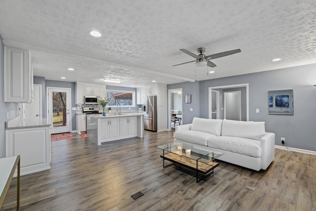 living room featuring a textured ceiling, ceiling fan, dark hardwood / wood-style floors, and sink