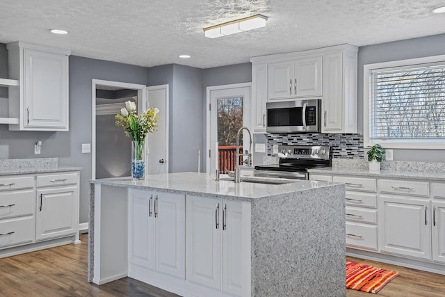 kitchen featuring a center island with sink, white cabinets, wood-type flooring, and appliances with stainless steel finishes