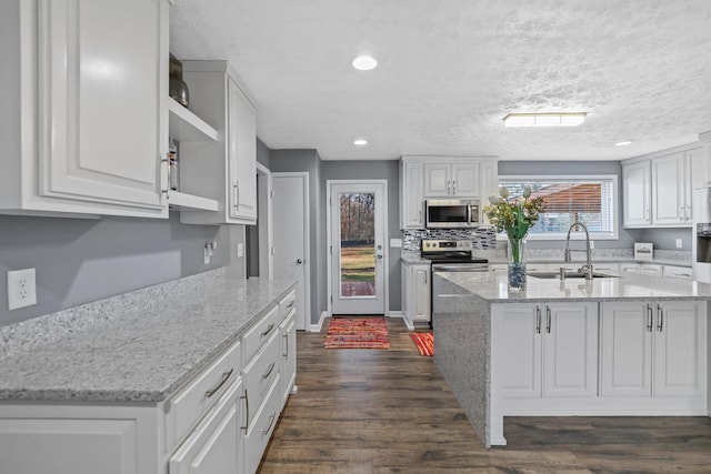 kitchen featuring white cabinetry, sink, light stone counters, and appliances with stainless steel finishes