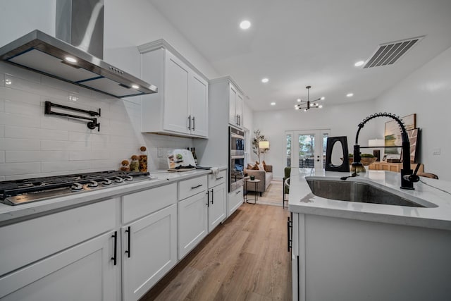 kitchen featuring sink, white cabinets, wall chimney range hood, and stainless steel gas stovetop