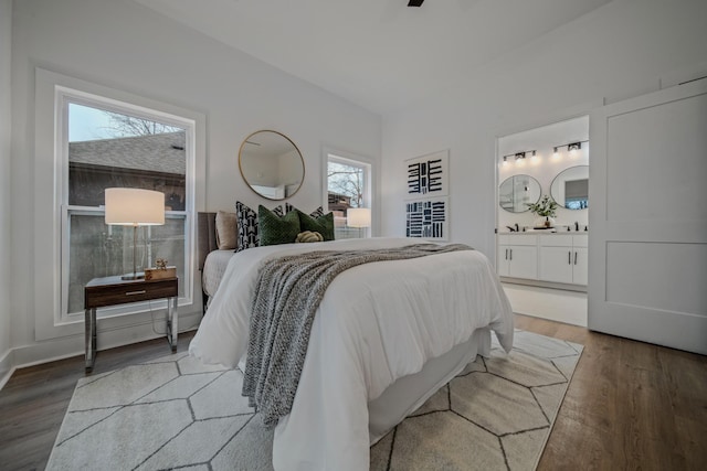 bedroom featuring hardwood / wood-style flooring, ensuite bathroom, and multiple windows