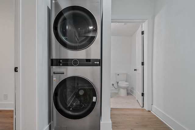 washroom with stacked washer / dryer and light hardwood / wood-style floors