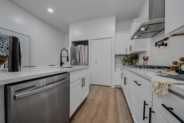 kitchen featuring white cabinets, light stone countertops, wall chimney range hood, and stainless steel appliances