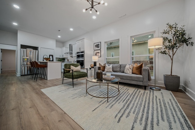 living room with light wood-type flooring and an inviting chandelier