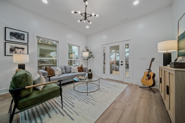 living room featuring a notable chandelier, french doors, and light hardwood / wood-style flooring