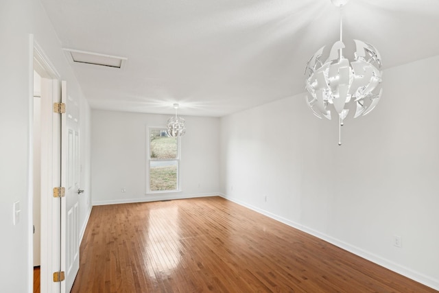 empty room with hardwood / wood-style flooring and a chandelier