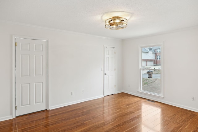 spare room with hardwood / wood-style flooring, ornamental molding, and a textured ceiling