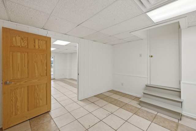 basement with a drop ceiling and light tile patterned flooring