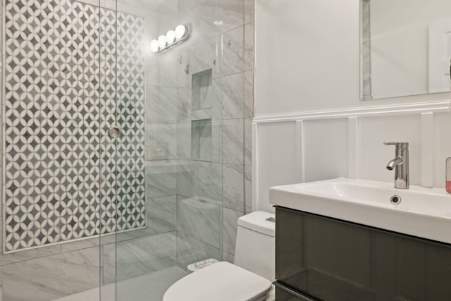 bathroom with vanity, tiled shower, and toilet