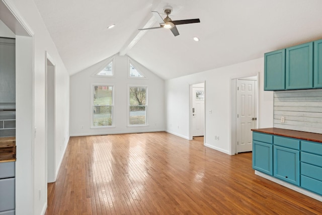 unfurnished living room with lofted ceiling with beams, ceiling fan, and light hardwood / wood-style floors