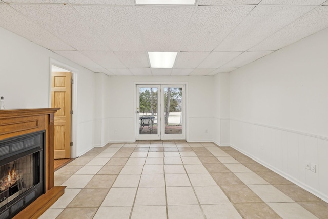 unfurnished living room with a drop ceiling and light tile patterned floors