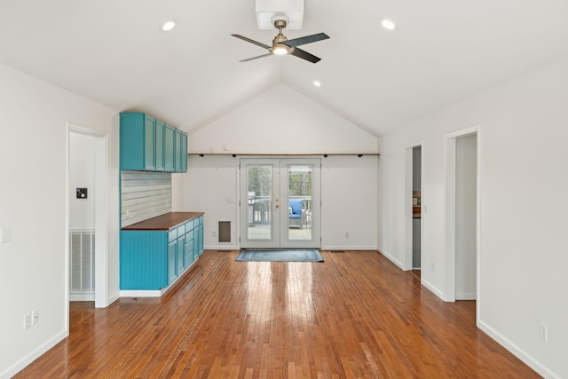 unfurnished living room featuring hardwood / wood-style floors, vaulted ceiling, french doors, and ceiling fan