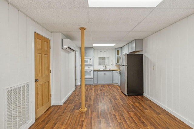 kitchen featuring sink, dark wood-type flooring, white cabinetry, an AC wall unit, and white appliances