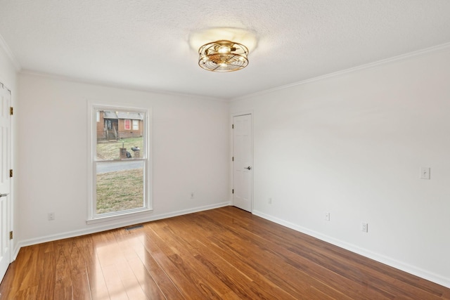 unfurnished room featuring wood-type flooring, ornamental molding, and a textured ceiling