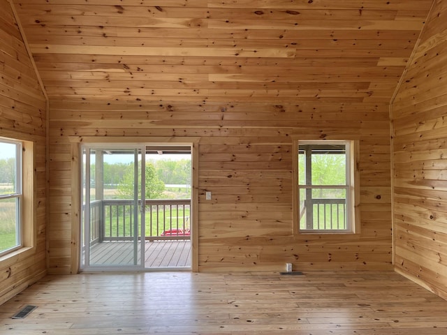 empty room featuring lofted ceiling, a healthy amount of sunlight, and light hardwood / wood-style floors