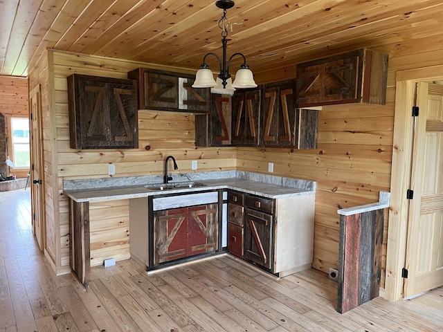 kitchen featuring sink, wood ceiling, wooden walls, a notable chandelier, and light hardwood / wood-style floors