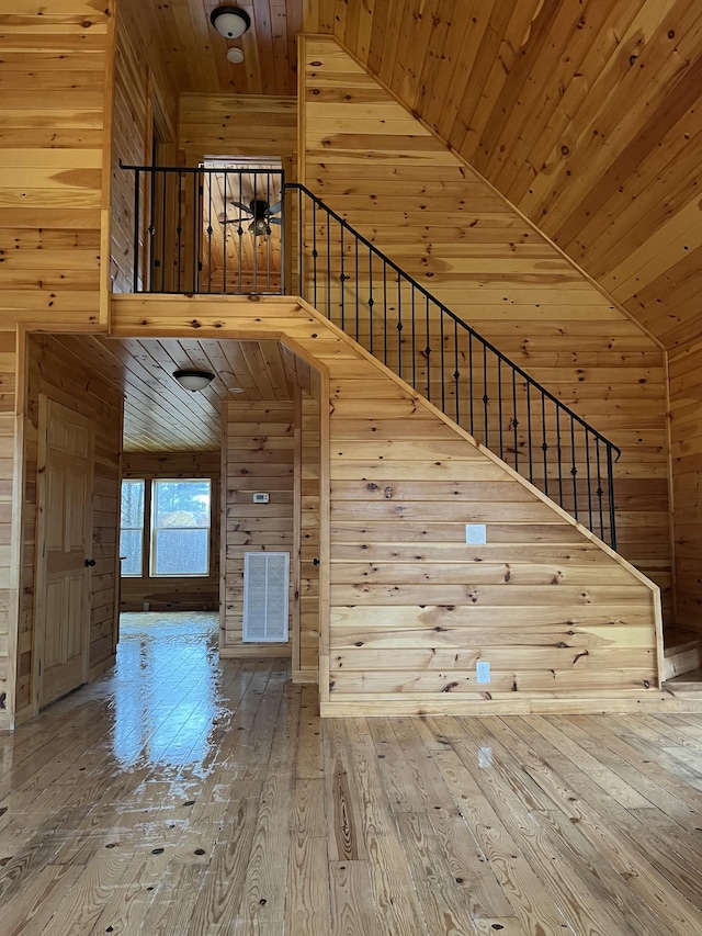 stairs featuring high vaulted ceiling, hardwood / wood-style floors, wood ceiling, and wood walls