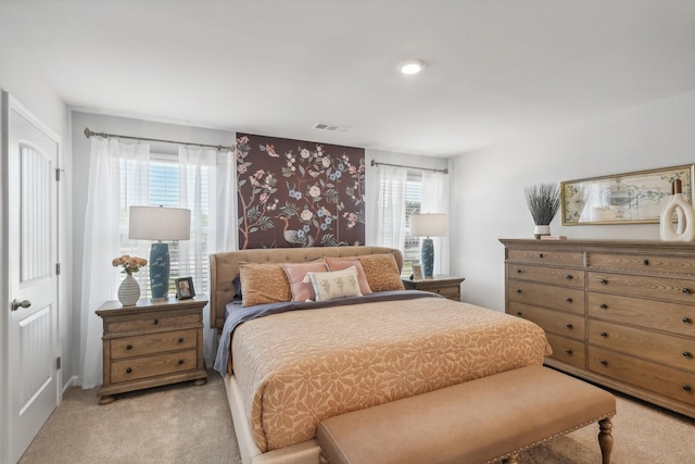 bedroom featuring visible vents, light colored carpet, and multiple windows