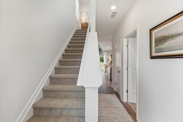 staircase with recessed lighting, wood finished floors, visible vents, and baseboards