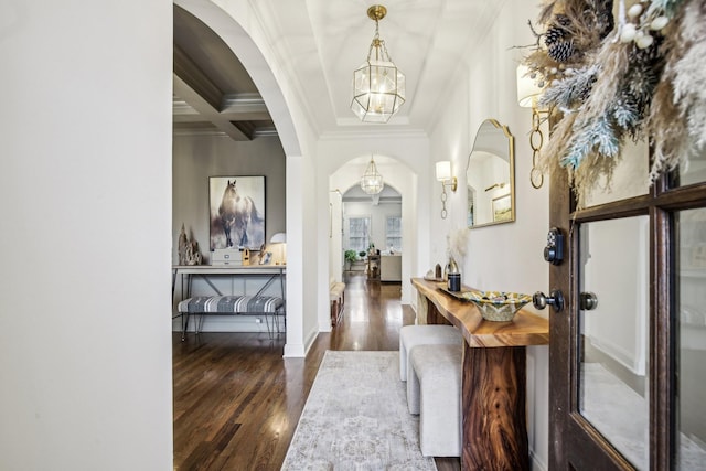 entrance foyer featuring beam ceiling, dark wood-type flooring, coffered ceiling, an inviting chandelier, and crown molding