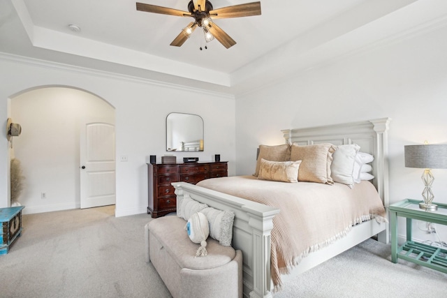 bedroom featuring ornamental molding, a tray ceiling, ceiling fan, and light colored carpet