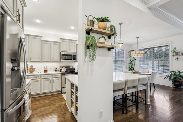 kitchen with appliances with stainless steel finishes, dark hardwood / wood-style flooring, tasteful backsplash, a breakfast bar, and pendant lighting