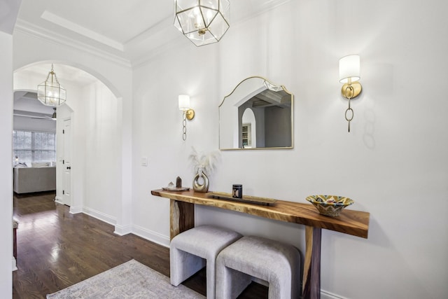 corridor with an inviting chandelier, dark wood-type flooring, and ornamental molding