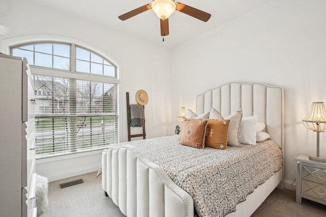 carpeted bedroom with ceiling fan, white refrigerator, and multiple windows