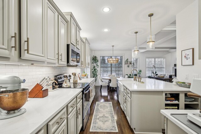 kitchen featuring dark hardwood / wood-style flooring, backsplash, gray cabinetry, stainless steel appliances, and hanging light fixtures