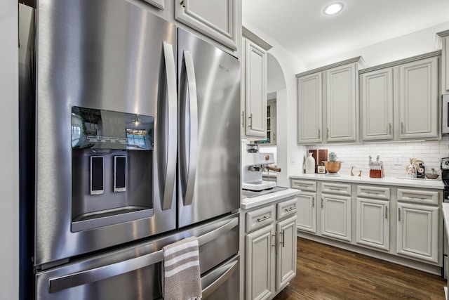 kitchen featuring stainless steel fridge, backsplash, dark hardwood / wood-style floors, and gray cabinetry