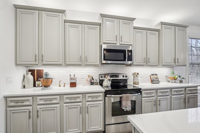 kitchen featuring stainless steel appliances, tasteful backsplash, and gray cabinetry