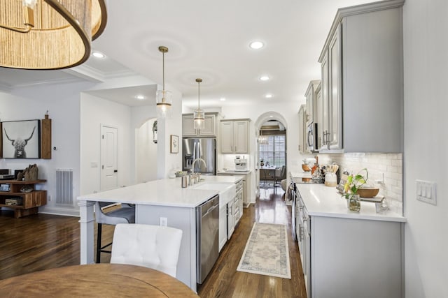 kitchen featuring gray cabinetry, an island with sink, decorative light fixtures, and appliances with stainless steel finishes