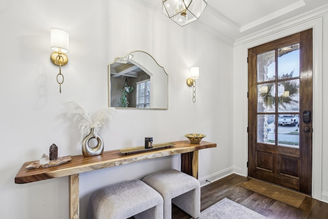 entryway featuring a chandelier, a wealth of natural light, crown molding, and dark wood-type flooring