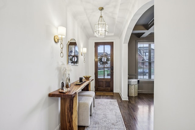 foyer entrance featuring beam ceiling, coffered ceiling, dark hardwood / wood-style floors, a notable chandelier, and ornamental molding