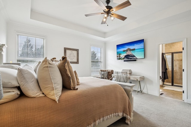 bedroom featuring a raised ceiling, ensuite bath, ceiling fan, and light carpet