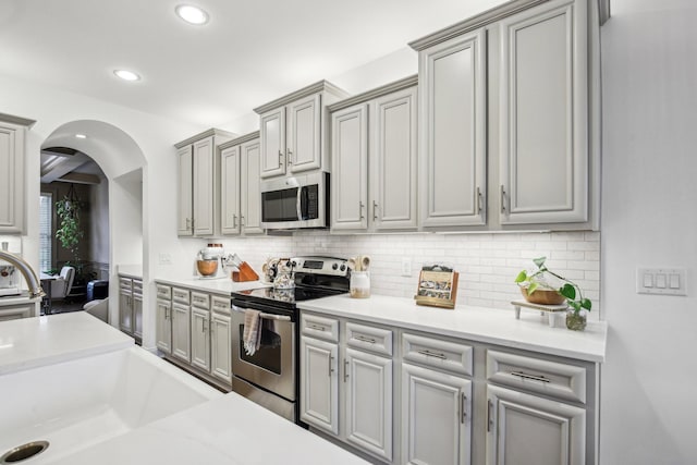 kitchen featuring decorative backsplash, gray cabinets, and appliances with stainless steel finishes